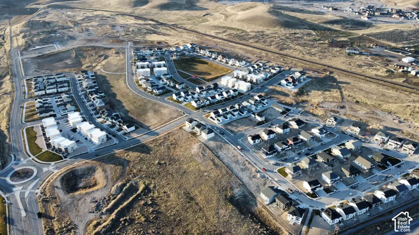 Aerial perspective of a planned residential development featuring paved road infrastructure, a roundabout, grid-patterned street layouts, and multi-unit housing clusters