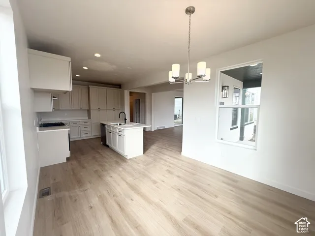 Kitchen featuring light-toned cabinetry, a center island with a sink, wood-finish flooring, recessed lighting, and a multi-light chandelier
