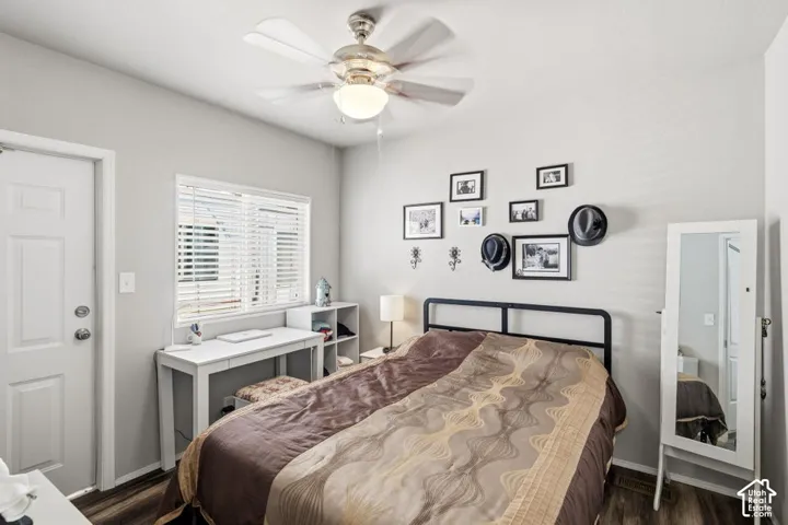 Neutral-toned interior room featuring wood-finish flooring, a multi-blade ceiling fan with integrated light fixture, and horizontal blind window coverings