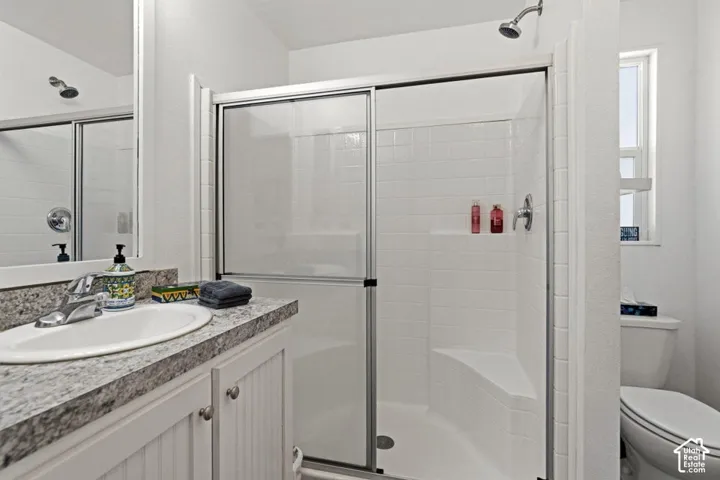 Bathroom featuring a vanity with a stone-finish countertop, white beadboard cabinetry, a walk-in shower with a built-in seat, and tile surround