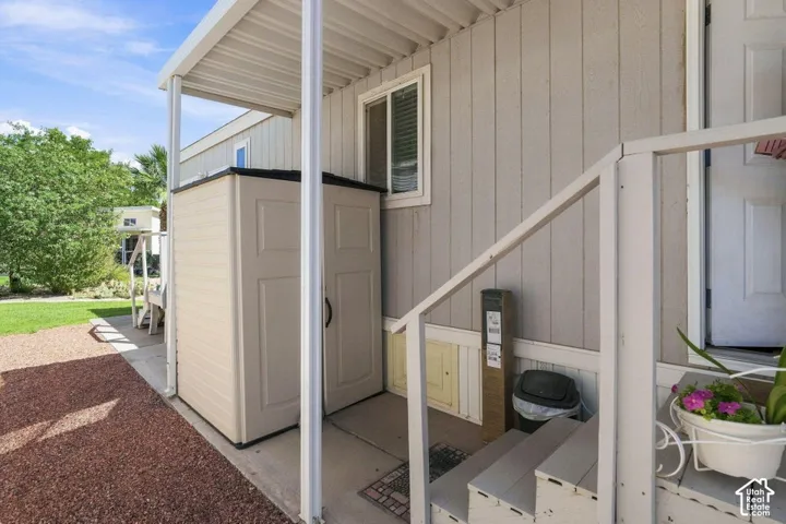 Exterior featuring vertical siding, metal-frame carport, gravel ground cover, and built-in exterior storage unit