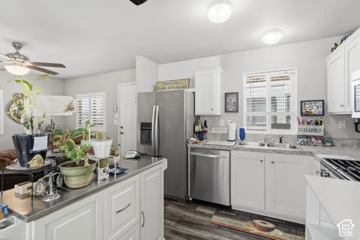 Kitchen featuring white shaker-style cabinetry, stainless steel appliances, speckled stone-finish countertops, wood-finish flooring, and a central kitchen island