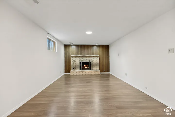 Brick fireplace with a metal screen, wood-finish wall paneling, and wood-finish flooring
