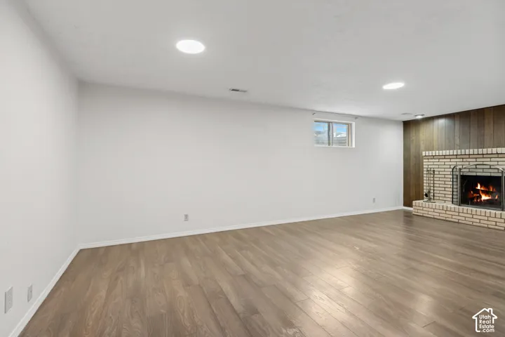 Interior space featuring wood-finish flooring, recessed lighting, and a brick fireplace surround with wood-panel accent wall