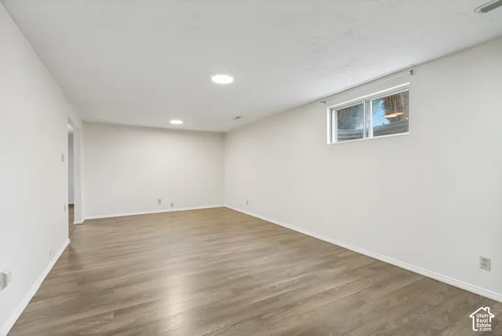Interior room featuring neutral wall paint, wood-finish flooring, recessed lighting, and a single sliding window