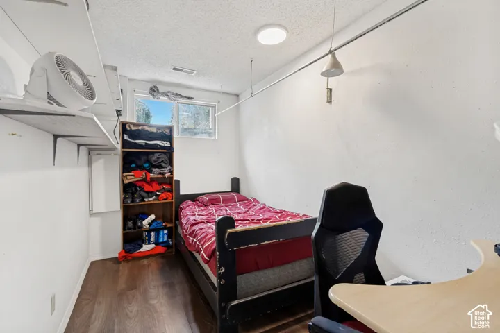 Room featuring wood-finish flooring, built-in wall shelving, a sliding window, and a ceiling-mounted light fixture
