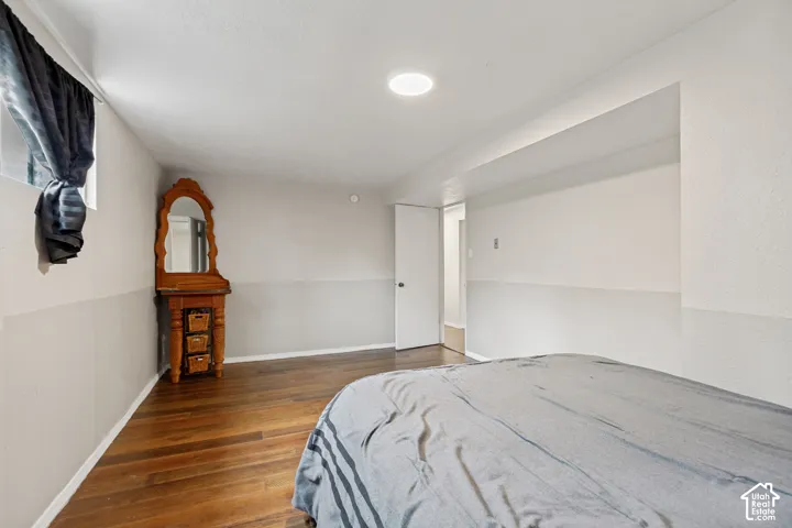 Room interior featuring wood-finish flooring, two-toned wall paint, recessed ceiling lighting, and a window with natural light
