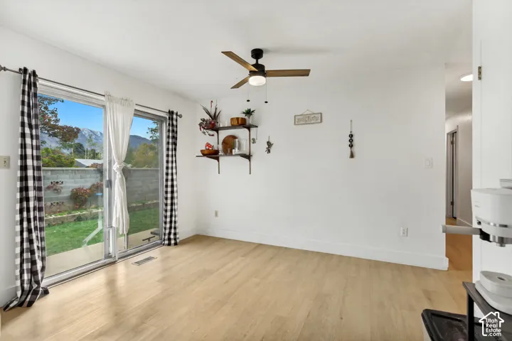 Sliding glass door, wood-finish flooring, ceiling fan with integrated lighting, and mountain scenery