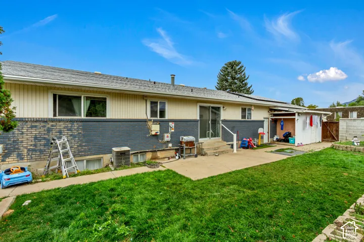 Exterior featuring a combination of horizontal siding and brick cladding, concrete patio, sliding glass door, and an attached covered storage area