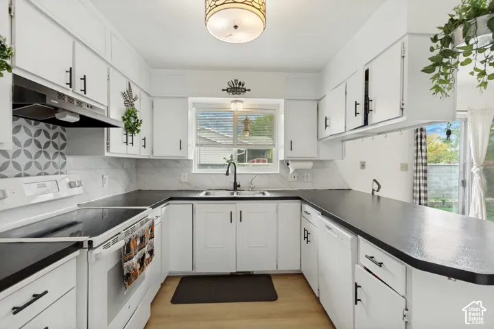 Kitchen featuring white cabinetry with matte black hardware, dark countertops, a geometric-patterned tile backsplash, and a double-basin sink with a matte black faucet