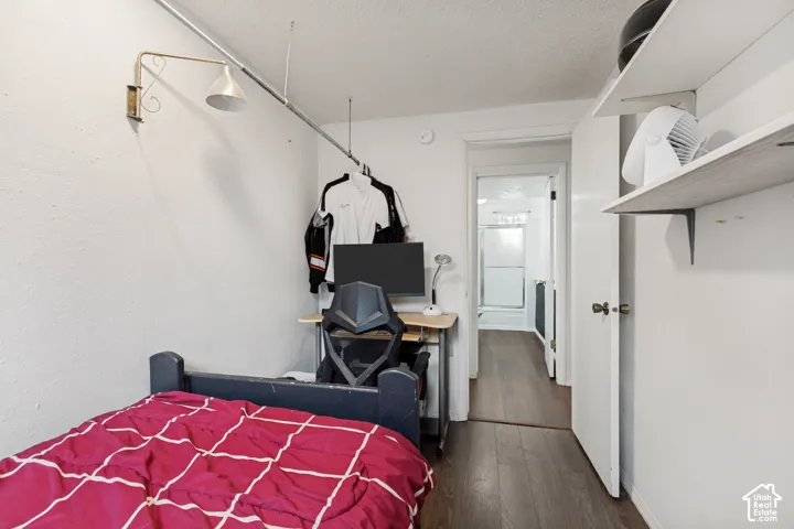 Room featuring wood-finish flooring, wall-mounted swing-arm light fixture, and white wall-mounted shelving