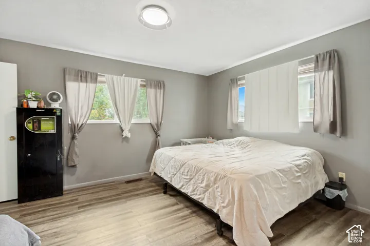 Room with wood-finish flooring, neutral-toned walls, and multiple dual-pane windows with sliding glass functionality