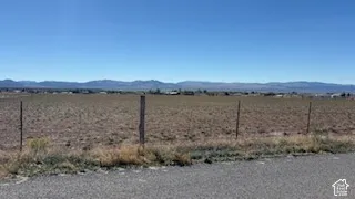 Expansive parcel of land featuring wire fencing and mountain backdrops