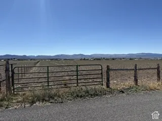 Expansive acreage featuring a metal tubular gate, post-and-wire fencing, and a mountain backdrop