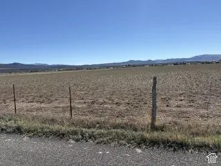 Expansive vacant acreage featuring level terrain, wire perimeter fencing, and mountain scenery