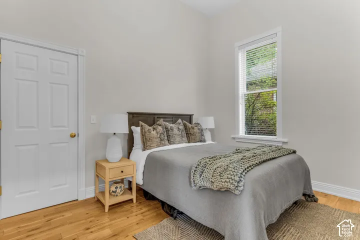 Room featuring wood-finish flooring, high ceilings, neutral wall color, and a single-hung window with casing