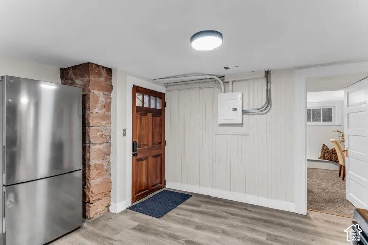 Entryway featuring a wood-finish entry door with multi-pane glazing, exposed stone pillar, wood-panel wall accents, and wide-plank wood-finish flooring