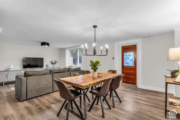 Wood-finish flooring, multi-light metal chandelier, and a solid wood door featuring a decorative glass inset