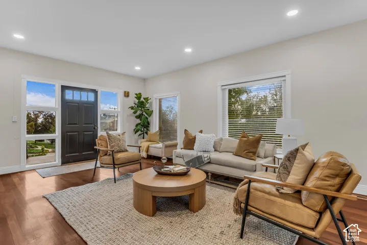 Solid wood-finish flooring, recessed lighting, expansive windows with integrated sidelights, and a paneled entry door with transom window