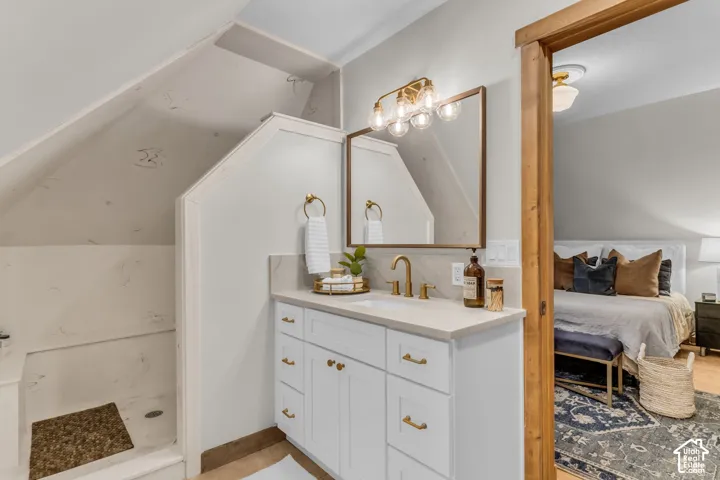 Bathroom vanity featuring a quartz countertop, white cabinetry with brass-toned hardware, a wall-mounted brass-toned faucet, and a rectangular mirror with a matching brass-toned frame