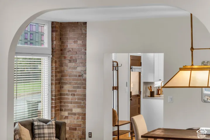 Arched architectural opening, exposed brick wall, multi-pane window with transom, and brass-finish pendant lighting