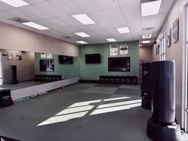 Expansive multipurpose studio featuring wall-to-wall mirrors, recessed drop-ceiling lighting, and segmented floor padding