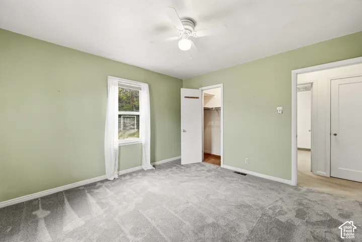 Neutral-toned carpeting, ceiling fan with integrated light fixture, and built-in closet storage