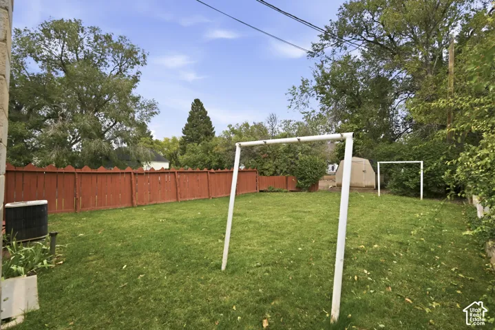Backyard featuring a grass lawn, perimeter wood fencing, and a detached storage structure