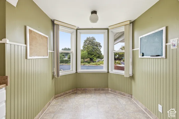 Bay window featuring multi-pane glass, beadboard wall paneling, tile flooring, and a central globe light fixture