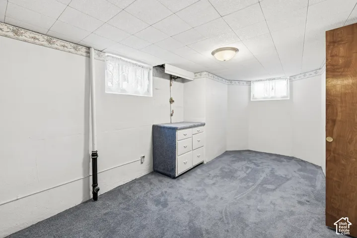 Interior space featuring a drop ceiling, wall-to-wall carpeting, built-in cabinetry, flush-mount lighting, and dual inset windows