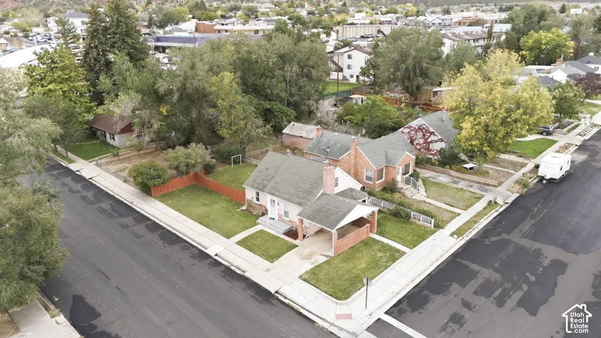 Corner lot residence featuring a brick exterior, attached carport, masonry chimney, and established landscaping with mature trees