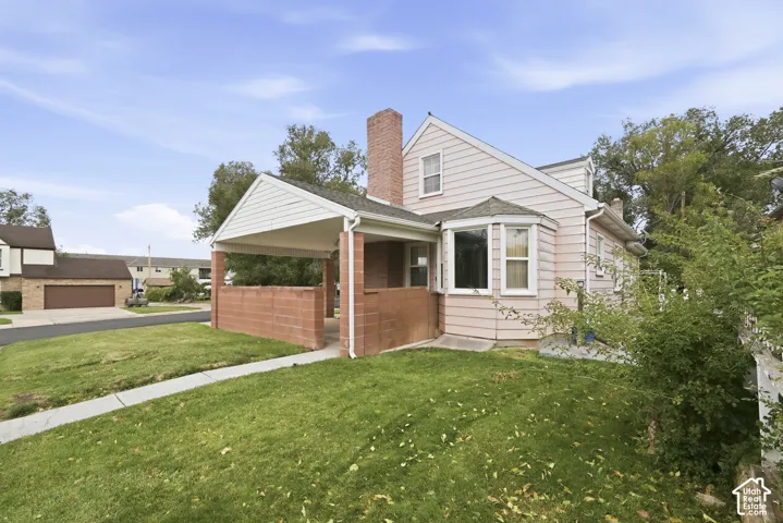 Exterior featuring horizontal siding, a brick chimney, a covered carport with masonry walls, and a bay window