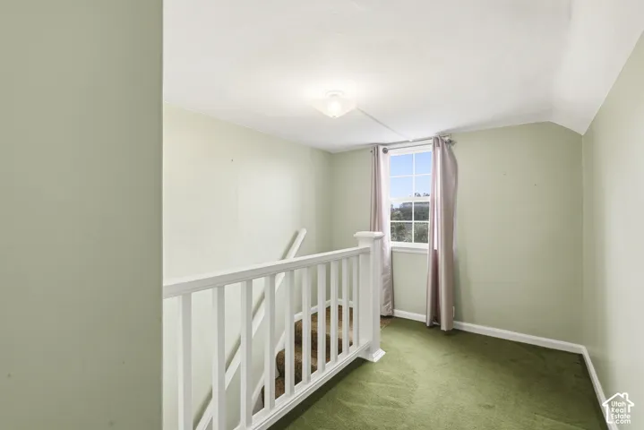 Landing area featuring carpeted flooring, a white wooden balustrade, a single window with muntins, and a flush-mount light fixture