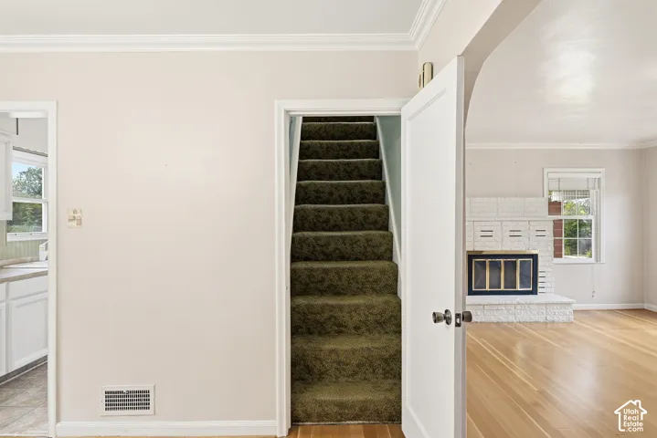 Wood-finish flooring, white painted brick fireplace with hearth, and arched architectural detailing