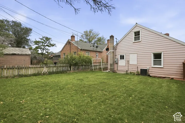 Backyard featuring a grass lawn, a wood-picket fence, and an exterior masonry chimney