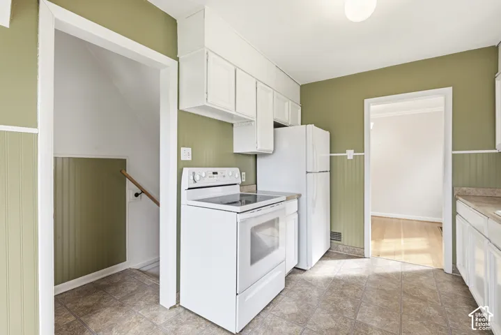 Kitchen featuring white cabinetry, solid-surface countertops, tile flooring, and vertical wall paneling