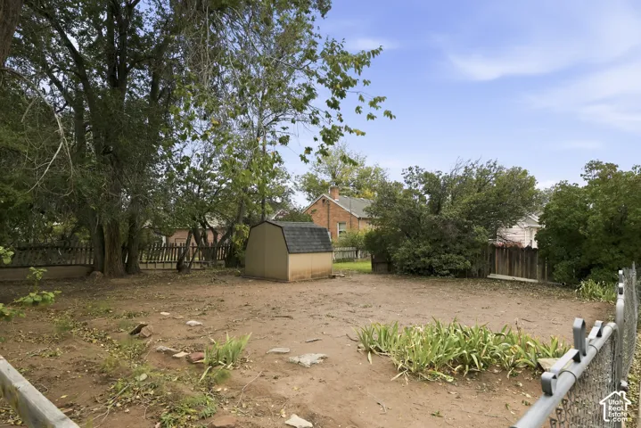 Backyard featuring a storage shed, mature trees, and perimeter chain-link and wood fencing