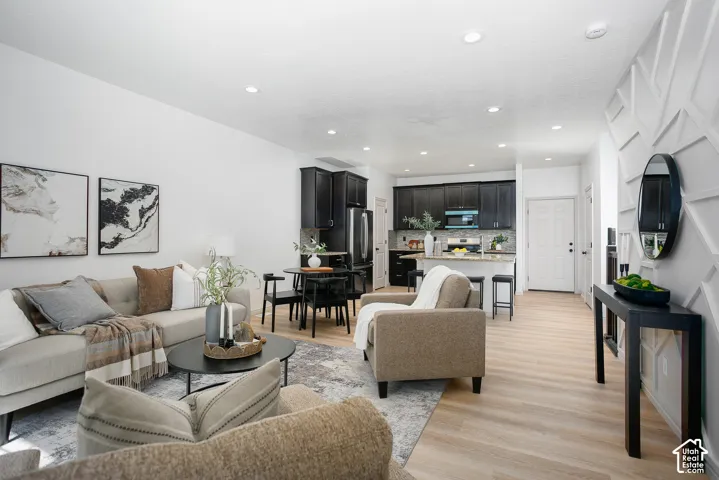 Open-concept interior featuring light wood-finish flooring, recessed lighting, and a geometric accent wall
