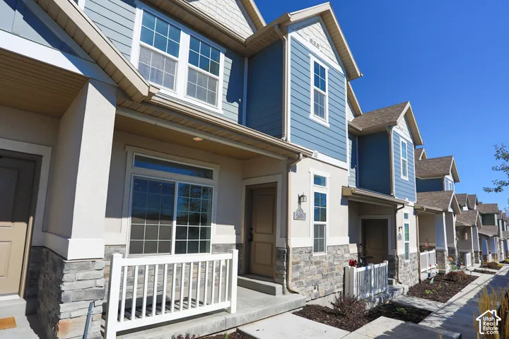 Multi-level exterior featuring a stone veneer facade, horizontal lap siding, shingle accents, concrete porches with white railings, and multi-pane windows