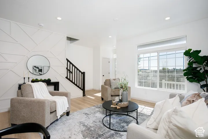 Geometric wall paneling, wood-finish flooring, recessed lighting, and a staircase featuring a dark-finish wood railing