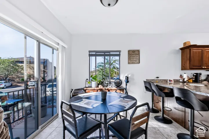 Sliding glass door, ceramic tile flooring, kitchen peninsula with stone-finish countertop, and recessed ceiling lighting