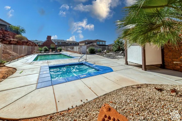 Outdoor recreation area featuring an in-ground pool, a tiled spa, concrete decking, and a covered pergola