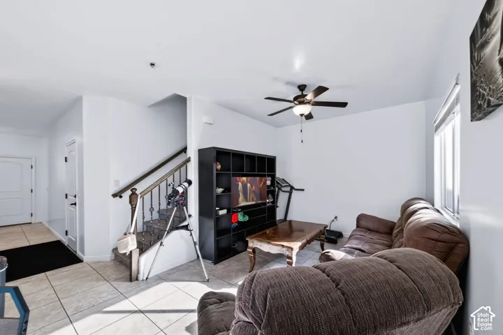 Interior area featuring tile flooring, a ceiling-mounted light fixture with fan, and a staircase with metal balusters