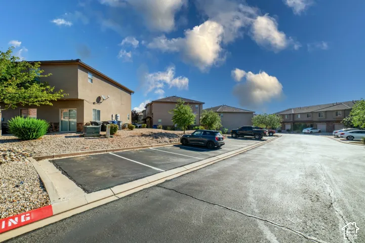 Stucco exterior siding, paved asphalt parking spaces, and low-maintenance rock landscaping