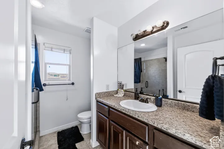Bathroom featuring a stone-composite countertop, dark wood-finish cabinetry, an oval under-mount sink, full-width vanity mirror, and three-bulb integrated vanity lighting