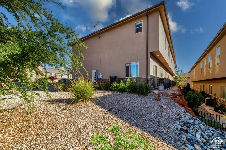 Multi-story stucco exterior with stone veneer accents, integrated sliding glass door, and low-maintenance rock landscaping featuring decorative gravel and mature shrubbery