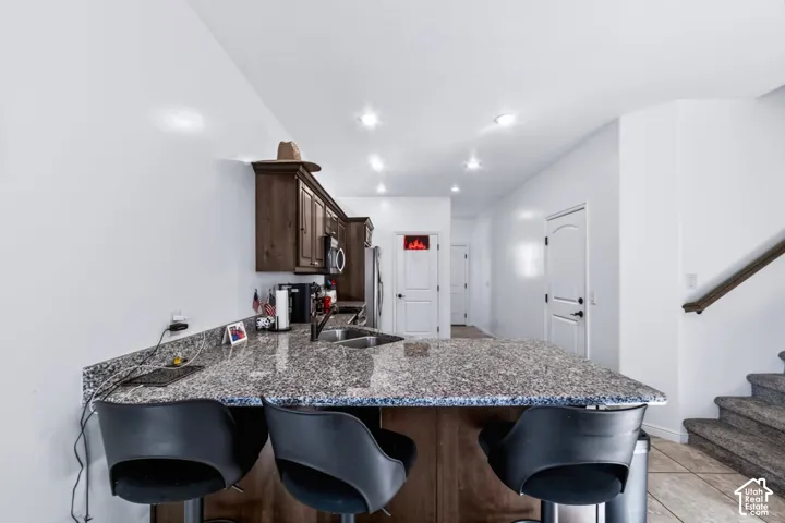 Kitchen featuring dark wood cabinetry, a stone-pattern countertop, dual-basin sink, and recessed lighting