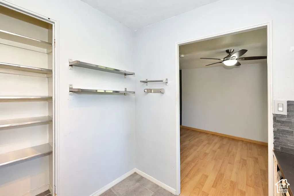 Built-in shelving, metallic wall-mounted storage racks, wood-finish flooring, and a ceiling fan with integrated lighting
