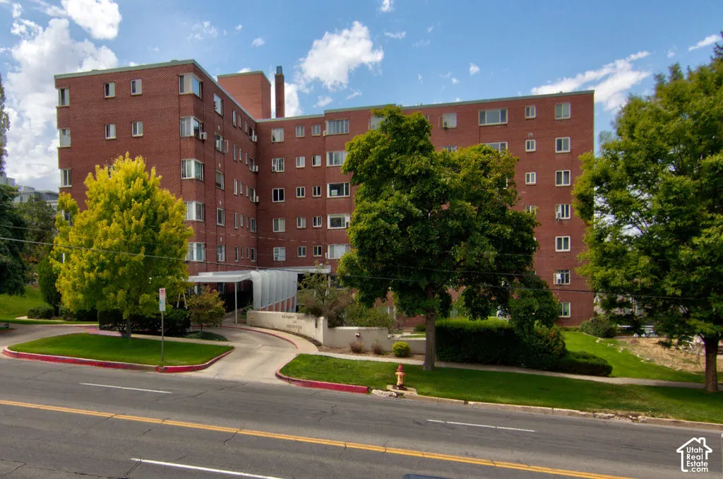 Mid-rise brick exterior featuring a covered entryway, multi-story facade, and mature landscaping