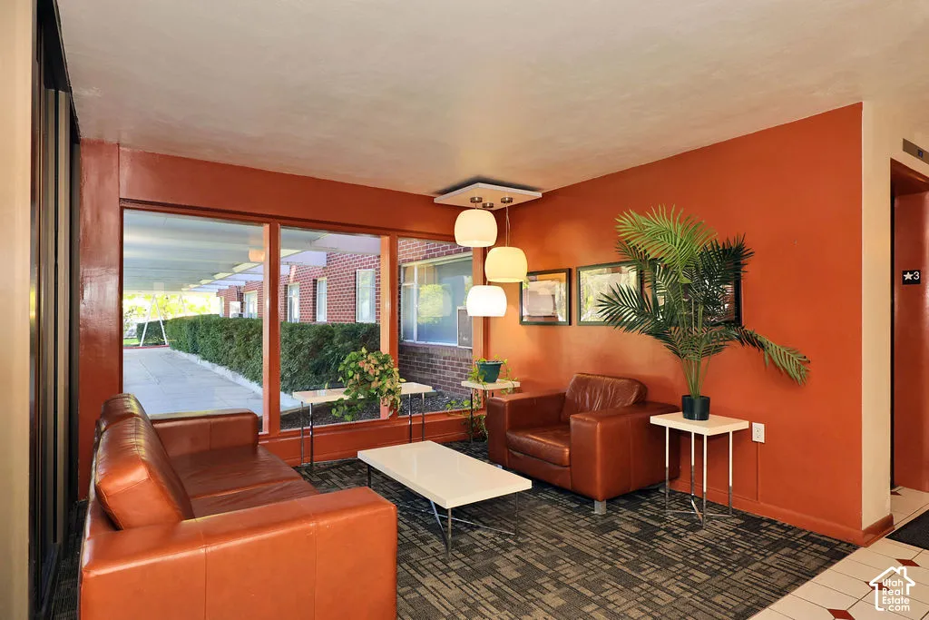 Expansive floor-to-ceiling windows, modern multi-pendant lighting fixture, patterned carpet flooring, and brick exterior finish